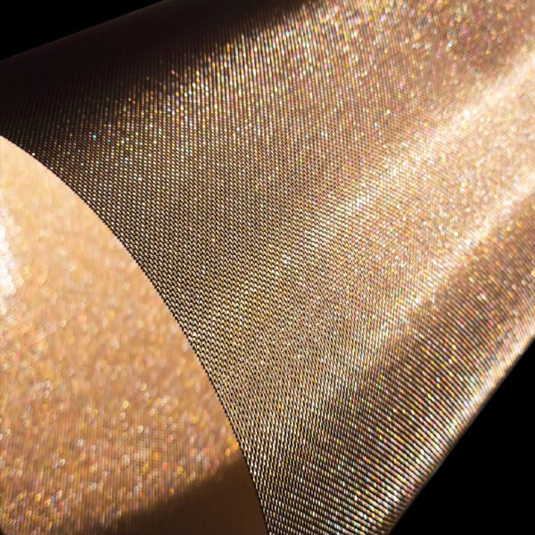 Dettaglio ravvicinato di una superficie lucida e glitterata dorata, con micro-punti di riflessi su un tessuto o supporto metallico sfumato.