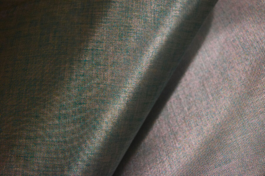 Primo piano di tessuto verde e lavanda intrecciato, con texture rigata e pieghe dovute al piegamento della stoffa.